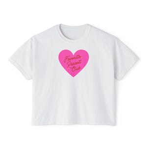 May include: White t-shirt with a crew neck and short sleeves. A pink heart graphic in the center features the text "Favorite Parent Club" in a cursive font. The shirt is made of a soft, comfortable material.