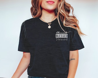 May include: A black t-shirt with a white graphic that says "Blessed Blessed Blessed". The model is wearing blue jeans and white sneakers.