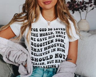 May include: White t-shirt with black text that reads "For God so loved the world, that he gave his only begotten Son, that whoever believes in him should not perish, but have everlasting life."