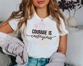 May include: White t-shirt with a floral design and the text "Courage is contagious" in black.