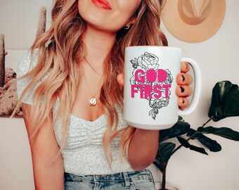 May include: White ceramic mug with a black floral design and the words "GOD FIRST" in pink lettering.