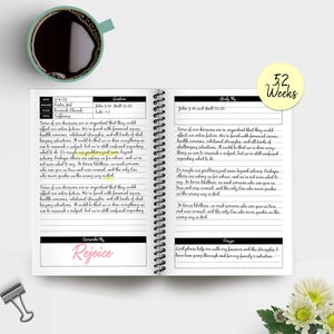 Może przedstawiać: Rozwinięcie dw&oacute;ch stron dziennika z czarno-białym spiralnym oprawieniem. Strony są wypełnione odręcznymi notatkami i wersetami biblijnymi. G&oacute;rna część prawej strony zawiera tekst "52 tygodnie". Dolna część lewej strony zawiera tekst "Raduj się".