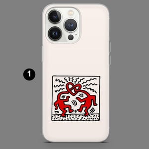 May include: A white phone case featuring a red Keith Haring-style graphic of two figures. One figure is dancing, and the other is connected to a series of wavy lines. The case has a clear border.