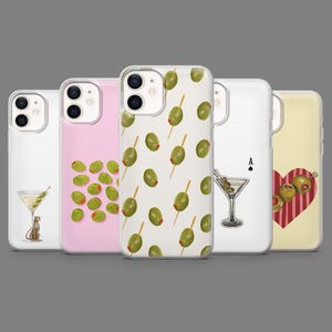 Può includere: Una collezione di custodie per telefoni con vari design. Una custodia presenta un martini con olive e un motivo leopardato, un'altra ha olive sparse e una terza mostra olive su spiedini. Altre custodie mostrano un bicchiere da martini e un cuore con olive.