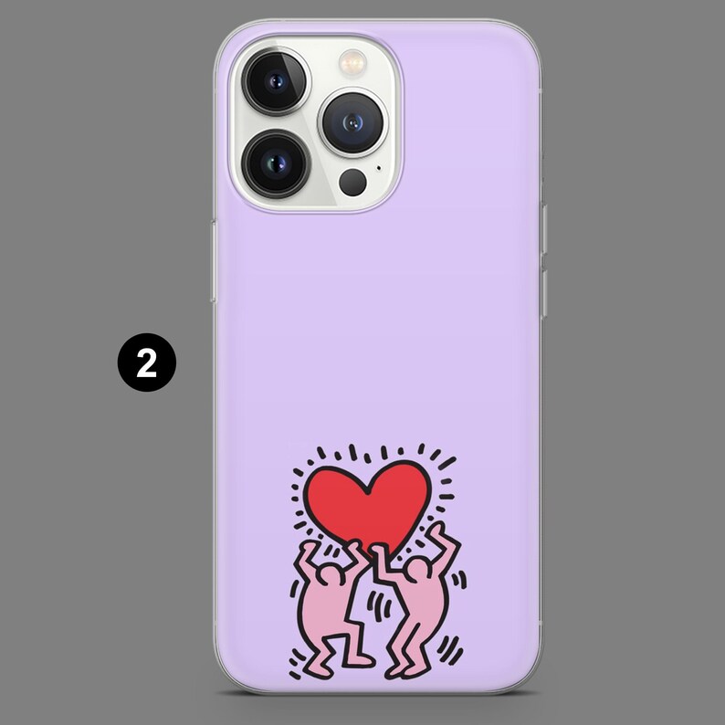 May include: A lavender phone case featuring a graphic of two figures holding a red heart. The case has a glossy finish and a camera cutout. The design is a pop art style.