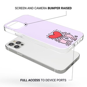 May include: A light purple phone case with a clear border, featuring a red heart and two figures in a Keith Haring-style design. The case is shown over a silver phone, with the text "SCREEN AND CAMERA BUMPER RAISED" and "FULL ACCESS TO DEVICE PORTS".
