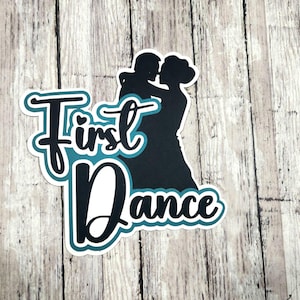 May include: A die-cut sticker featuring a black silhouette of a couple embracing while dancing. The text "First Dance" is written in a bold, black script font with a teal outline and a white border, positioned over the couple's silhouette.