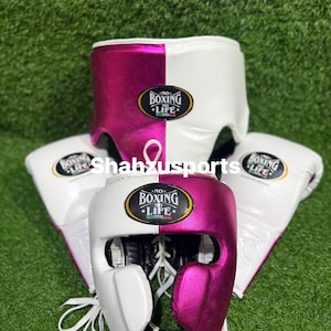 May include: Boxing gear set including a white and pink head guard, a groin protector, and boxing gloves. Each item features the text "NO BOXING NO LIFE" in a circular emblem. The set is displayed on a green surface.