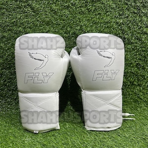 Pu&ograve; includere: Un paio di guantoni da boxe bianchi con la scritta "FLY" stampata in nero. Ogni guanto presenta una grafica di una figura alata. I guantoni sono su uno sfondo di erba verde.
