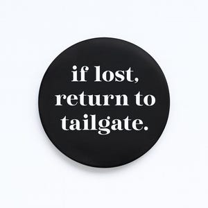 Puede incluir: Un botón redondo negro con texto blanco que dice "if lost, return to tailgate."