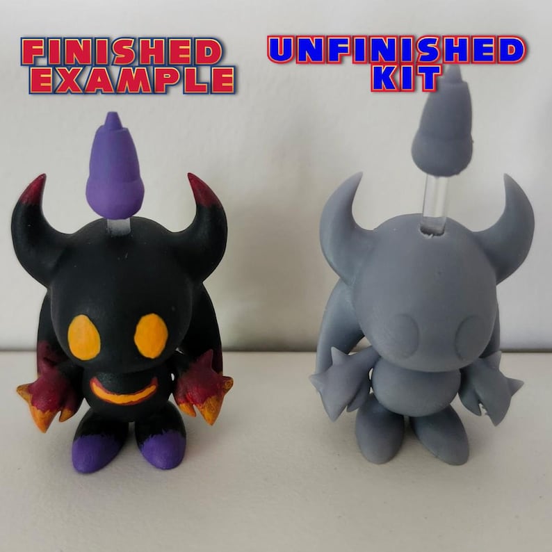 May include: A finished and unfinished 3D printed figurine of a black and purple character with horns and a pointed head. The finished figurine is painted black with red and purple accents. The unfinished figurine is grey and unpainted. The text "FINISHED EXAMPLE" is above the finished figurine and the text "UNFINISHED KIT" is above the unfinished figurine.