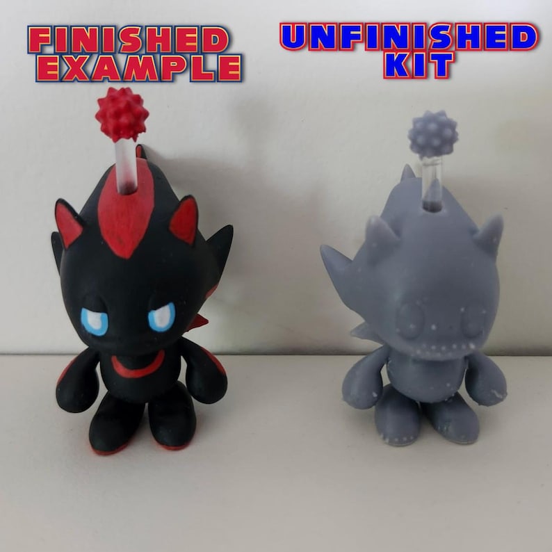 May include: A finished and unfinished 3D printed model of a black and red character with a spiky head. The finished model is painted black and red, while the unfinished model is grey. The text "FINISHED EXAMPLE" is above the finished model, and the text "UNFINISHED KIT" is above the unfinished model.