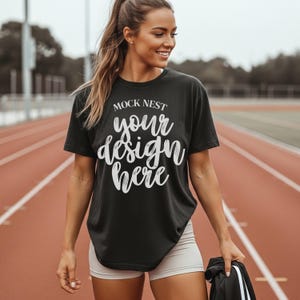 May include: Black t-shirt with the text "MOCK NEST your design here" in white script. The shirt is worn with light-colored shorts. The image is taken on a red track.