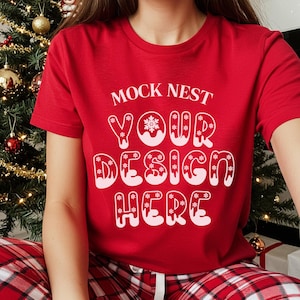 Może przedstawiać: Czerwona koszulka z białym napisem "MOCK NEST YOUR DESIGN HERE" w kształcie płatka śniegu. Koszulka z krótkim rękawem jest połączona z czerwono-białymi spodniami od piżamy w kratę. W tle widoczna jest choinka.