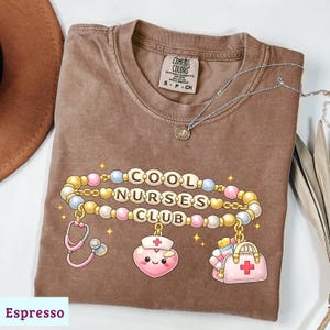 Könnte beinhalten: Ein Set aus drei Keramikbechern mit gesprenkelter, matter Oberfläche. Die Becher sind in Creme-, Hellgrau- und Dunkelgrautönen gehalten. Jeder Becher hat ein schlichtes, minimalistisches Design und einen abgerundeten Henkel.