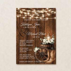 May include: A wedding invitation card featuring a dark brown wood plank background with string lights at the top. It displays the text Katelynn Jane Crawford and Michael Blair Lewis, a wooden barrel, a wagon wheel, and brown cowboy boots.