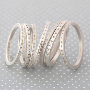 Könnte beinhalten: Ein Satz von sechs silbernen Ringen mit einem gepunkteten Muster. Die Ringe sind übereinander gestapelt.