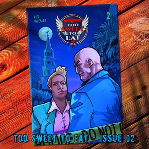 May include: Comic book cover with a blue background featuring two characters, a blonde person in a pink shirt and teal jacket, and a bald person in a blue suit. The title "TOO SWEET TO EAT" is displayed with wings. The text "ISSUE 02" is also visible.