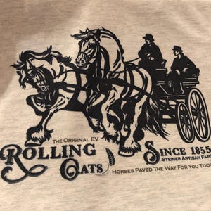 May include: Black and white illustration of two horses pulling a carriage with two people inside. The text "The Original EV Rolling Oats Since 1855 Steiner Artisan Farm Horses Paved The Way For You Today" is printed below the image.