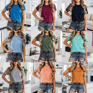 May include: Nine solid-color t-shirts in various shades, including blue, burgundy, black, light blue, green, teal, gray, peach, and brown. Each shirt has short sleeves and is paired with denim shorts. The shirts are displayed on a model.