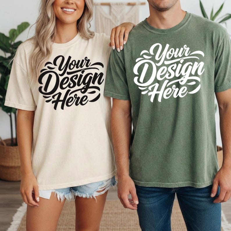 May include: Two short-sleeved t-shirts, one cream-colored and the other olive green, each with the text "Your Design Here" in a stylized script. The shirts are worn by two people, and the overall style is casual and relaxed.