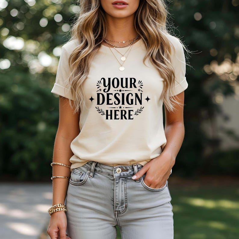 May include: A beige t-shirt with short sleeves and a crew neck. The shirt has a black graphic that says "Your Design Here" with a floral design around the text.