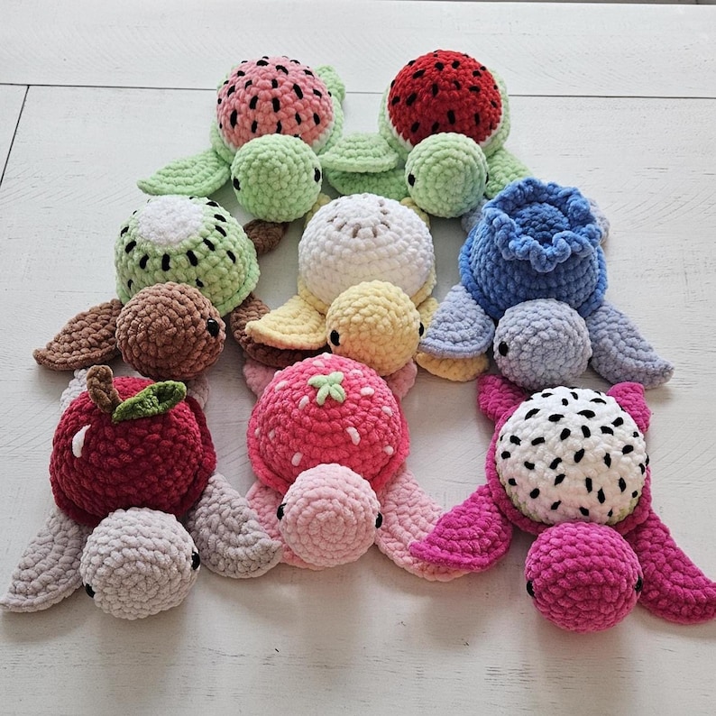 May include: A collection of handmade crochet turtles, each designed to resemble different fruits. The turtles feature various colors, including green, red, pink, and brown, with details mimicking watermelon, kiwi, apple, strawberry, dragon fruit, and blueberry.