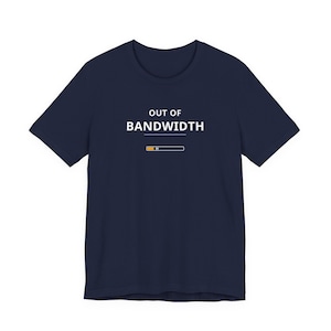 Puede incluir: Camiseta azul marino con el texto blanco "OUT OF BANDWIDTH" sobre un gráfico de barra de carga amarilla y blanca. La camiseta tiene cuello redondo y mangas cortas.