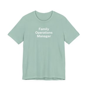 May include: A light green t-shirt with the text "Family Operations Manager" in white. The shirt has short sleeves and a crew neck. The text is centered on the front of the shirt.