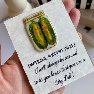 May include: A card featuring a cartoon of two pickles in a jar. The text says "EMOTIONAL SUPPORT PICKLE, I will always be around to let you know that you are a Big Dill!"