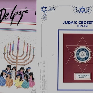 May include: A cross-stitch pattern booklet titled De Grazia featuring a menorah with children in colorful clothing on the left and a Judaic Crosstitch Shalom pattern with a Star of David and the text The Shuman Family on the right side.