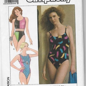 May include: Simplicity sewing pattern number 9210 for a swimsuit. The pattern includes three different styles: a two-piece swimsuit with a black and pink top and a green bottom, a one-piece swimsuit with a blue and pink geometric pattern, and a one-piece swimsuit with a blue and pink polka dot pattern. The pattern is suitable for sewing on an overlock/serger machine.