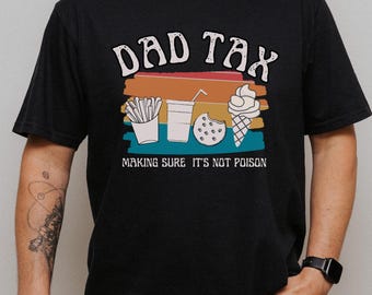 May include: Black t-shirt with a graphic that reads "DAD TAX" above illustrations of fries, a drink, a cookie, and an ice cream cone. The text "MAKING SURE IT'S NOT POISON" is below the illustrations.