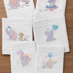 May include: White baby washcloths with embroidered elephant designs. Each washcloth features a different elephant illustration, including an elephant wearing a crown, flying a plane, holding a balloon, and more. The elephants are in various colors, including purple, pink, and gray.