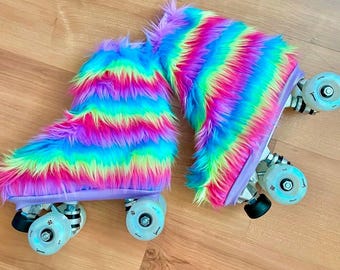 Può includere: Un paio di pattini a rotelle con coperture in finta pelliccia arcobaleno. I pattini hanno una base lilla chiaro e ruote trasparenti. La pelliccia è un vivace mix di rosa, giallo, verde, blu e viola.