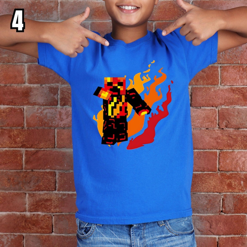 K&ouml;nnte beinhalten: Ein blaues T-Shirt mit einem pixeligen Charakterdesign und Flammen in Rot-, Orange- und Gelbt&ouml;nen. Die Figur ist schwarz und rot. Die Zahl 4 befindet sich in der oberen linken Ecke.