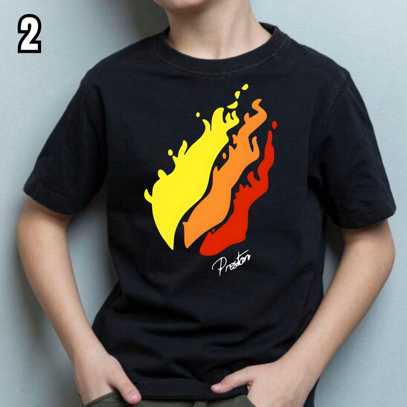 K&ouml;nnte beinhalten: Schwarzes T-Shirt mit einem Flammen-Design in Gelb, Orange und Rot. Das Wort "Preston" ist in Kursivschrift unter den Flammen geschrieben. Die Zahl "2" befindet sich in der oberen linken Ecke.