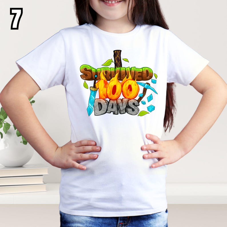 K&ouml;nnte beinhalten: Wei&szlig;es T-Shirt mit dem Text "Survived 100 Days" in einem farbenfrohen Cartoon-Design. Die Grafik enth&auml;lt ein Schwert, eine Spitzhacke und Bl&auml;tter. Die Zahl "7" befindet sich in der oberen linken Ecke.