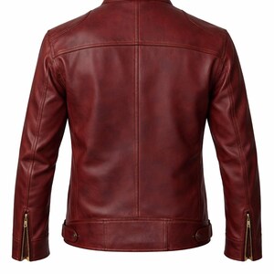 A burgundy leather jacket with a stand-up collar, visible stitching, and zippered sleeves. The back view showcases a tailored fit with a clean, minimalist design. The jacket has a classic, timeless style.