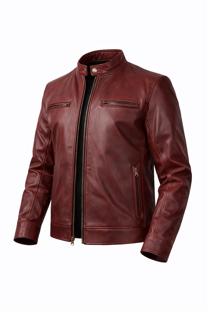 A burgundy leather jacket with a stand-up collar and a full-length zip. The jacket features two zipped chest pockets and two zipped hand pockets. The sleeves have a tailored fit. The jacket is made of smooth, supple leather.