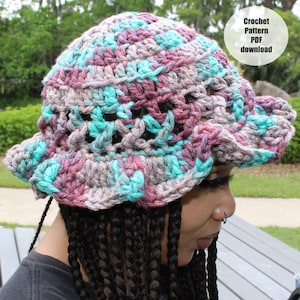 May include: A handmade crochet hat in shades of teal, purple, and gray. The hat has a wide brim and a textured design. The image includes the text "Crochet Pattern PDF download".