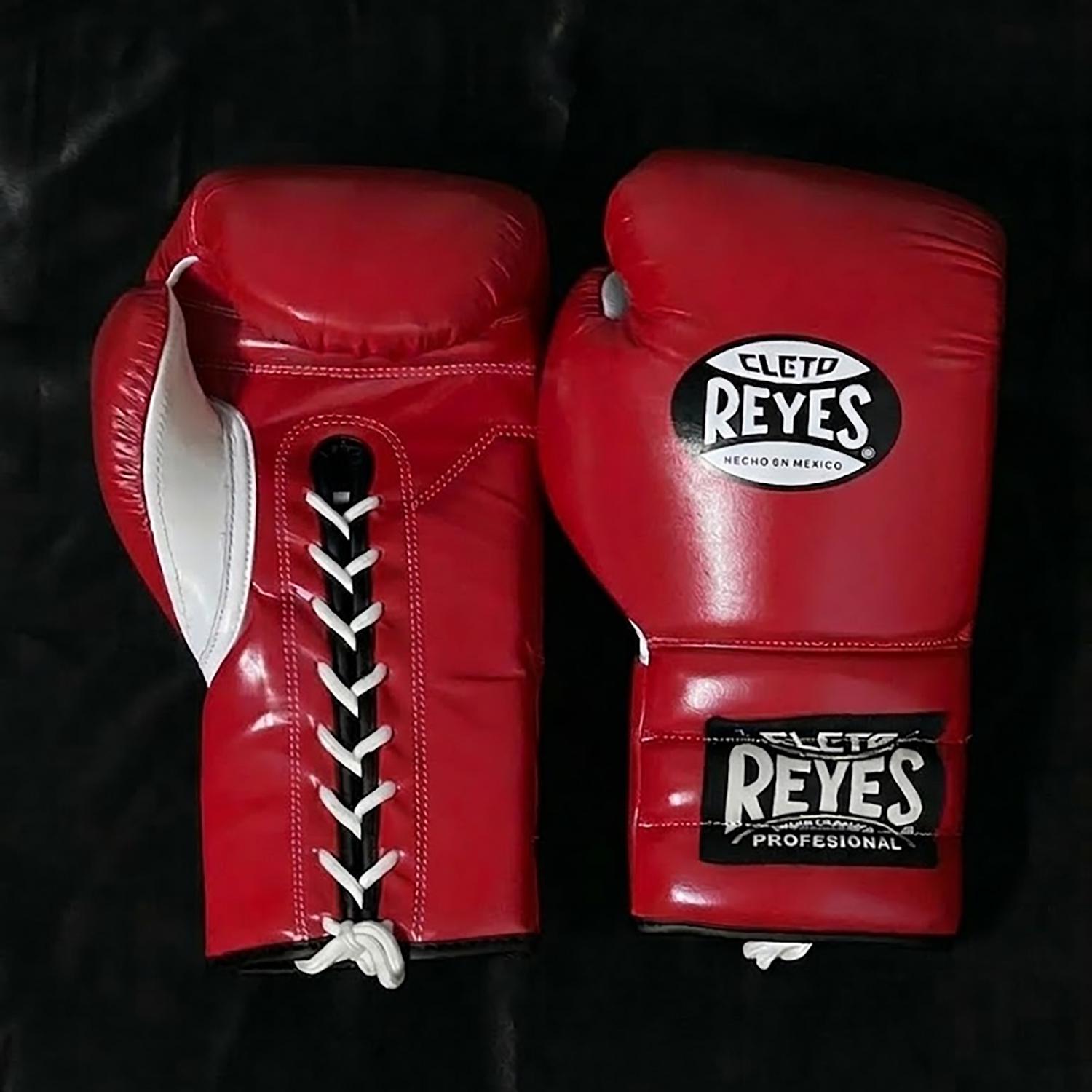 Peut inclure: Une paire de gants de boxe rouges avec des lacets blancs et des panneaux latéraux blancs. Les gants présentent le logo Cleto Reyes en noir et blanc sur le poignet et le dos de la main, avec le texte "CLETO REYES HECHO EN MEXICO" visible.