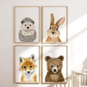 Op de afbeelding: Set van vier aquarel dierendrukken met een egel, een konijn, een vos en een beer. Elke print is ingelijst in een eenvoudige houten lijst en heeft een witte achtergrond.