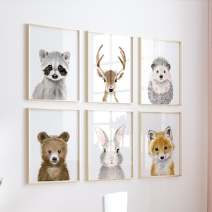May include: A set of six framed animal prints featuring a raccoon, deer, hedgehog, bear, rabbit, and fox. The prints are in a white room with a white table and chairs.