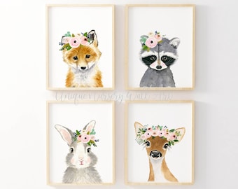 May include: Set of four watercolor animal prints featuring a fox, raccoon, rabbit, and deer, each wearing a pink floral crown. The prints are framed in light wood frames and are perfect for a nursery or child's room.