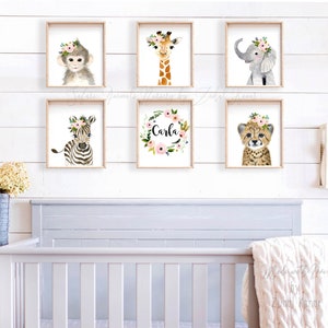 May include: A set of six nursery prints featuring watercolor illustrations of animals with floral crowns. The prints include a monkey, giraffe, elephant, zebra, cheetah, and a floral wreath with the name "Carla".