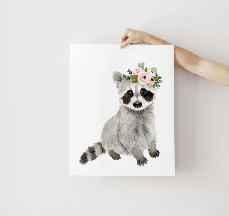 May include: A watercolor painting of a raccoon wearing a pink and green floral crown. The raccoon is sitting on a white background.