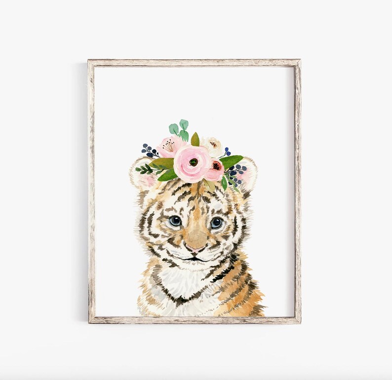 Pode incluir: Uma pintura em aquarela de um filhote de tigre usando uma coroa de flores rosa. O filhote de tigre tem listras marrons e pretas e olhos azuis. O fundo &eacute; branco.