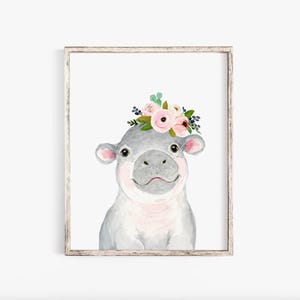 Pode incluir: Uma pintura em aquarela de um hipop&oacute;tamo cinza com o nariz rosa e uma coroa floral de flores rosa e brancas. O hipop&oacute;tamo est&aacute; olhando diretamente para o espectador.