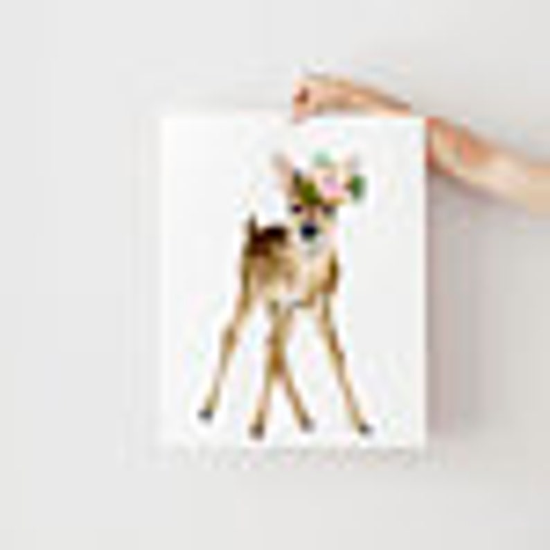 May include: A watercolor painting of a fawn with brown and white fur. The fawn is standing on a white background.